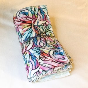 May include: A stack of colorful reusable cloths with a floral pattern. The cloths are folded and tied together with a string.