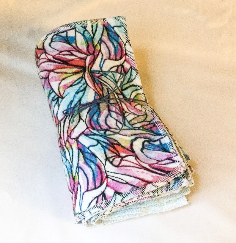 May include: A stack of colorful reusable cloths with a floral pattern. The cloths are folded and tied together with a string.