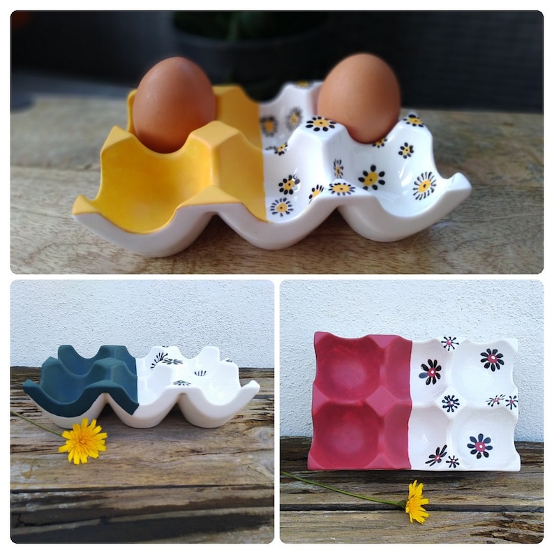 May include: Three ceramic egg holders in different colors and designs. The first is yellow and white with black floral designs, the second is dark green and white with black floral designs, and the third is red and white with black floral designs.