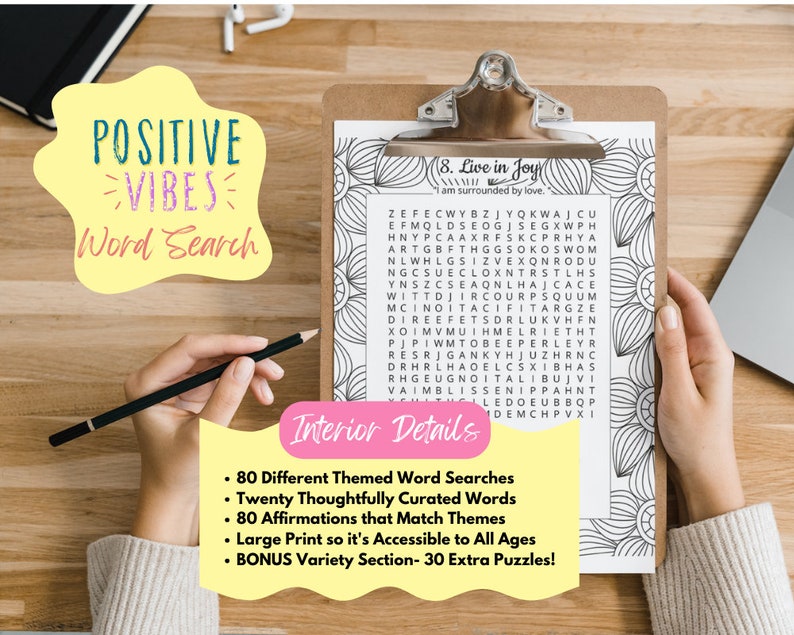 May include: A printable word search puzzle with a yellow and black title "POSITIVE VIBES Word Search". The puzzle features a grid of letters with the words "Live in Joy" and "I am surrounded by love." printed above the grid. The puzzle is on a clipboard with a black pencil on top of it. The background is a wooden table.