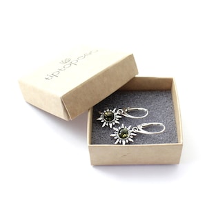 May include: A pair of silver earrings with green gemstone sunburst designs in a small brown box with the text "tiptopee" on the lid.