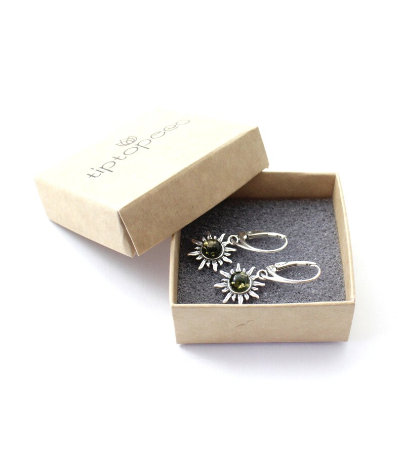 May include: A pair of silver earrings with green gemstone sunburst designs in a small brown box with the text "tiptopee" on the lid.