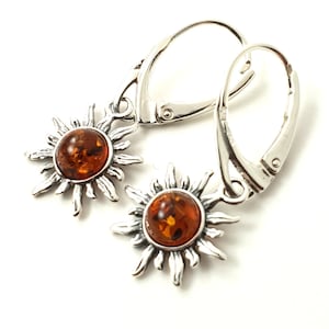 May include: A pair of silver earrings with amber sun pendants. The earrings have a hook closure.