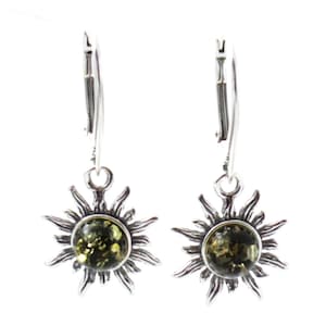 May include: A pair of silver earrings with green amber stones set in a sunburst design. The earrings have leverback closures.