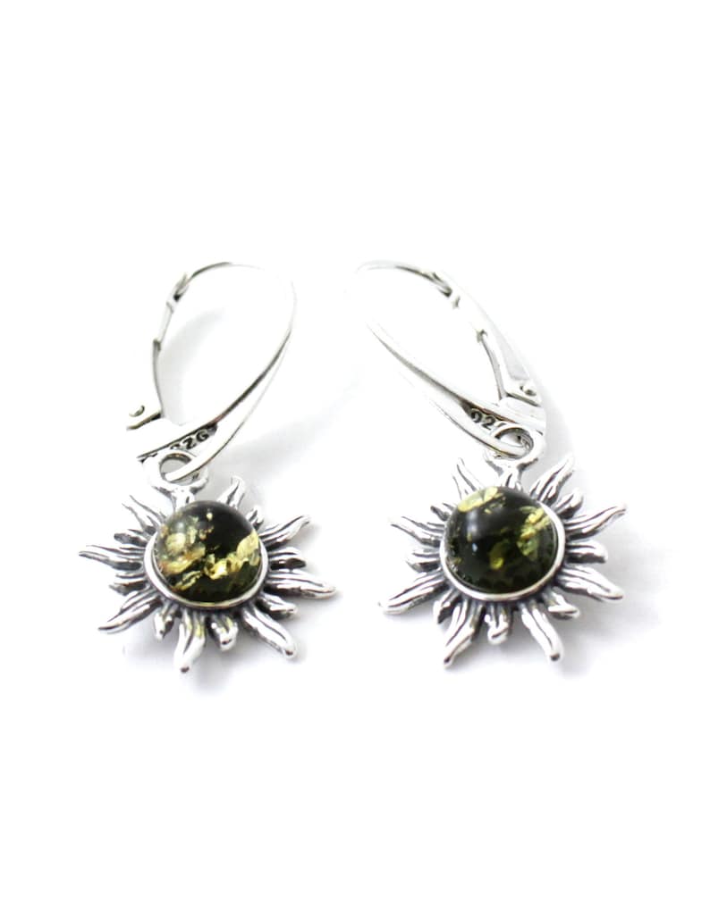 May include: A pair of silver dangle earrings with a green amber stone set in a sunburst design.
