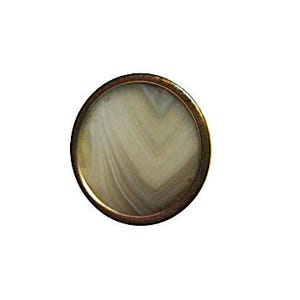 May include: A round, decorative button with a bronze-colored metal frame. The button's center features a swirling pattern of beige and white, resembling natural stone or agate. The design is circular and symmetrical.