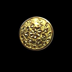 May include: A gold-colored metal button with a raised floral design. The button features a central flower surrounded by leaves and vines.