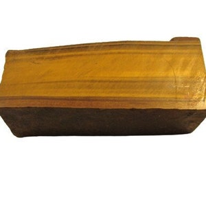 May include: A rectangular block of tiger's eye gemstone with a smooth, polished surface. The stone has a rich golden brown color with dark brown stripes.