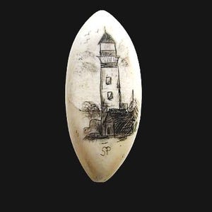 May include: An oval-shaped, off-white object featuring a black ink drawing of a lighthouse with a small building at its base. The drawing includes birds in the sky and the initials SP inscribed near the bottom edge of the surface.