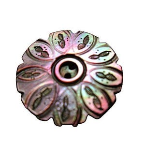 May include: A round, iridescent mother-of-pearl button featuring a scalloped edge and a central circular indentation with two holes. The surface displays a floral-like pattern of carved, petal-shaped segments with dark, etched detailing.