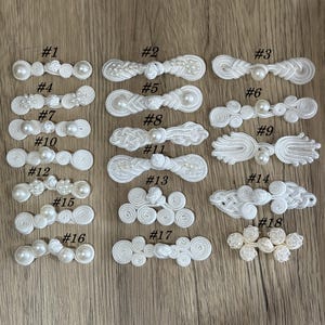 May include: A collection of white decorative closures, each with a unique design. The closures feature various shapes, including knots, loops, and pearl accents. Numbers 1 through 18 are printed on the image, indicating different styles.