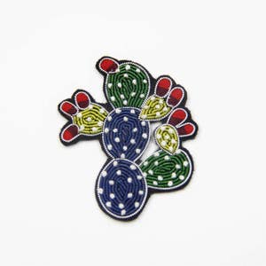 May include: A colourful embroidered cactus patch featuring green, blue, yellow, red and white thread. The cactus is a popular motif for clothing, bags and other accessories.