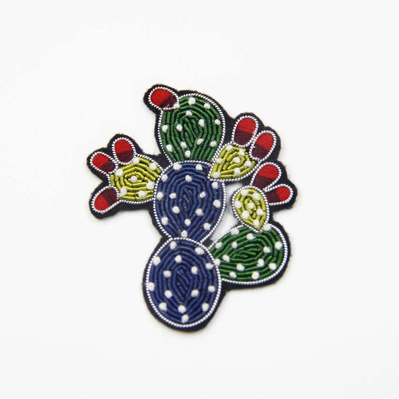 May include: A colourful embroidered cactus patch featuring green, blue, yellow, red and white thread. The cactus is a popular motif for clothing, bags and other accessories.