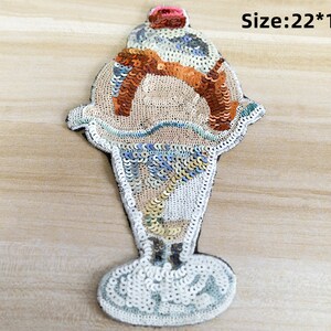 May include: A colourful sequined ice cream cone patch with a cherry on top. The patch is 22 cm by 13 cm.