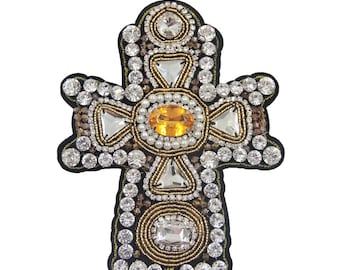 May include: A large, ornate cross-shaped patch with a gold and silver beaded design. The center of the cross features a large, yellow gemstone surrounded by smaller white pearls. The patch is 16 inches by 12 inches.