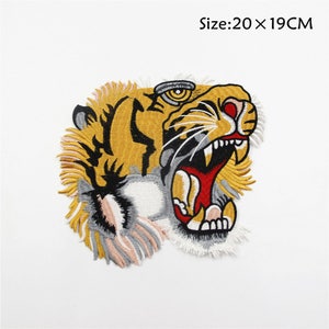 May include: Embroidered iron-on patch featuring a yellow and black tiger with a red open mouth. The patch is 20 x 19 cm.