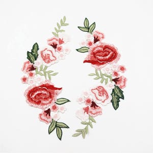 May include: Two embroidered floral patches with red and white flowers and green leaves.