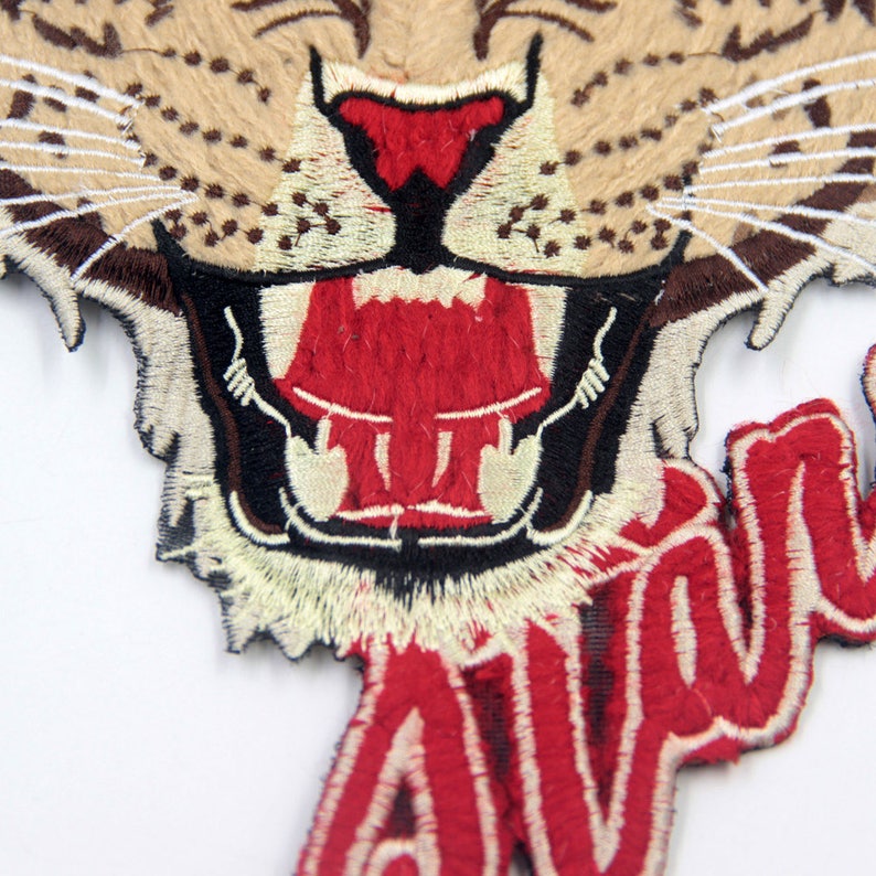 May include: Embroidered iron-on patch featuring a snarling tiger head with a red mouth and white teeth. The word "AVALANCHE" is embroidered in red below the tiger's head.