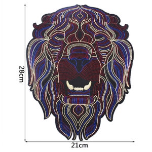 May include: A black, red, blue, and gold embroidered lion head patch. The patch is 21 cm wide and 28 cm tall.