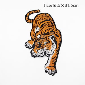 Op de afbeelding: Een geborduurde strijkpatch met een gedetailleerde oranje en zwarte tijger met witte strepen. De tijger bevindt zich in een hurkende positie met zijn kop naar de zijkant gedraaid. De patch is 16,5 cm bij 31,5 cm.