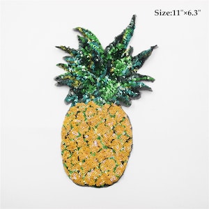 Può includere: Un toppa a forma di ananas di paillettes gialle e verdi, che misura 28 cm x 16 cm.