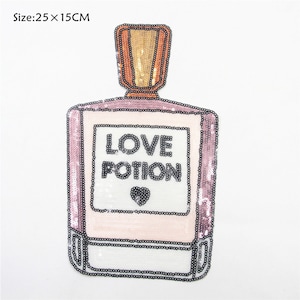 Puede incluir: Un parche de plancha de lentejuelas rosa y blanco con forma de frasco de perfume con el texto "LOVE POTION" y un pequeño corazón.