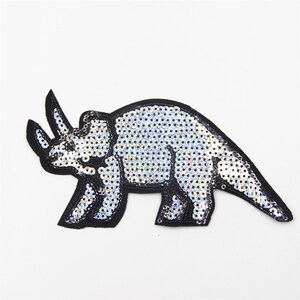May include: A silver sequined iron-on patch of a triceratops dinosaur.