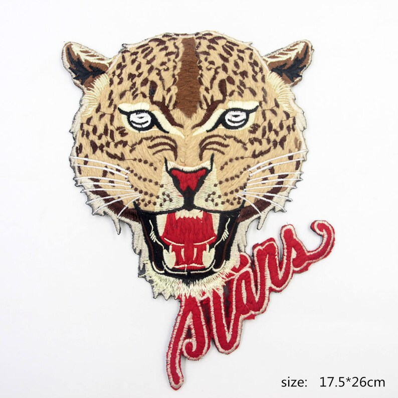 May include: Embroidered iron-on patch featuring a snarling leopard head with a red mouth and white teeth. The word "Stars" is embroidered in red below the leopard's head. The patch measures 17.5 by 26 centimeters.