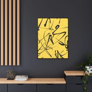 Puede incluir: Una pieza de arte mural rectangular con un fondo amarillo vibrante y líneas y garabatos abstractos negros dibujados a mano. La obra de arte está encerrada en un marco oscuro y delgado, creando un contraste marcado con la superficie amarilla.