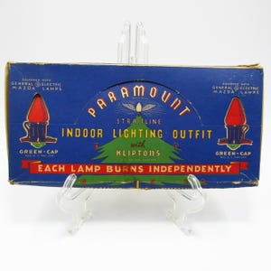 May include: Vintage Paramount Straitline Indoor Lighting Outfit box. The blue box features the text "Paramount" and "Indoor Lighting Outfit" with a Christmas tree graphic. The box also includes the text "Each lamp burns independently."