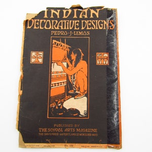 May include: Vintage book cover titled "Indian Decorative Designs" by Pedro J. Lemos. The cover features a black background with orange text and illustrations. The image depicts a person weaving, with pottery in the foreground. Published by The School Arts Magazine.