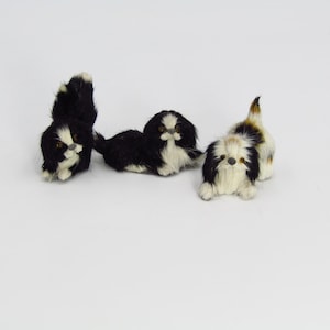 May include: Three plush toy dogs, one black and white, one brown and white, and one black and white with a brown patch on its back.