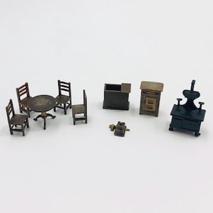 May include: A miniature furniture set including a round table with three chairs, a small rectangular cabinet, a tall cabinet with a door, a tiny square object, and a black stove with a raised back panel, all featuring dark brown and black finishes.