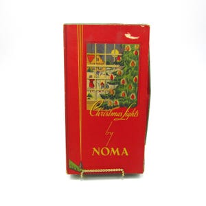 May include: A vintage red box of Christmas lights by NOMA. The box features a colorful illustration of a Christmas tree and a snowy winter scene viewed through a window. Gold vertical stripes and text are on the front.