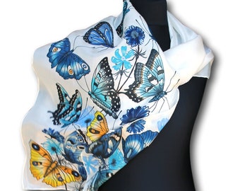 May include: White silk scarf with a blue and yellow butterfly print. The scarf is folded and draped over a black mannequin.