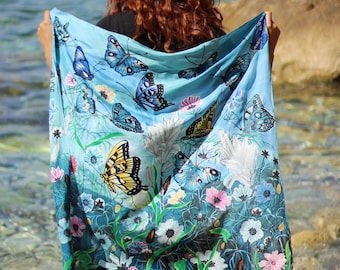 May include: A blue and green patterned scarf with butterflies and flowers. The scarf is draped over a person's shoulders.