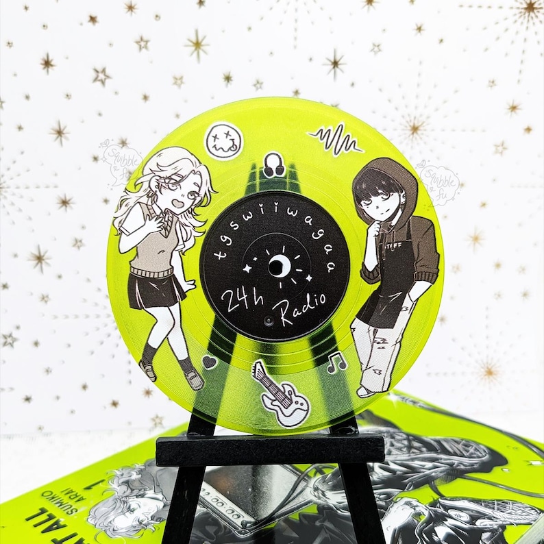 May include: A neon green vinyl record with anime-style illustrations of two people, a guitar, and musical notes. The record has the text "24h Radio" and other Japanese text. The record is displayed on a small black easel.