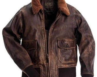 May include: A brown leather bomber jacket with a shearling collar. The jacket has two front pockets with button closures, a zip-up front, and ribbed cuffs and hem. The leather has a distressed appearance.