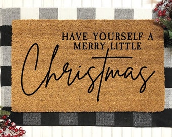 Könnte beinhalten: Eine braune Kokosmatte mit schwarzem Text, der "Have yourself a merry little Christmas" lautet. Die Fußmatte liegt auf einem schwarz-weiß karierten Hintergrund.