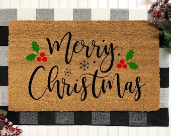 May include: A brown coir doormat with the text "Merry Christmas" in black script. The text is decorated with green holly leaves and red berries.
