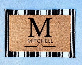May include: A black and white striped doormat with the letter "M" and the name "MITCHELL" in black text.