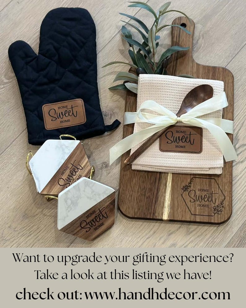 May include: A black oven mitt, wooden cutting board, coasters, and a kitchen towel with a wooden spoon. The items are labeled with "Home Sweet Home". The cutting board has a sprig of greenery and the towel is tied with a ribbon.