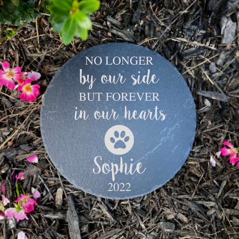 K&ouml;nnte beinhalten: Ein grauer Schieferstein-Gedenkstein mit dem Text "NO LONGER by our side BUT FOREVER in our hearts" und einem Pfotenabdruck. Der Name "Sophie" und das Jahr "2022" sind ebenfalls in den Stein graviert.