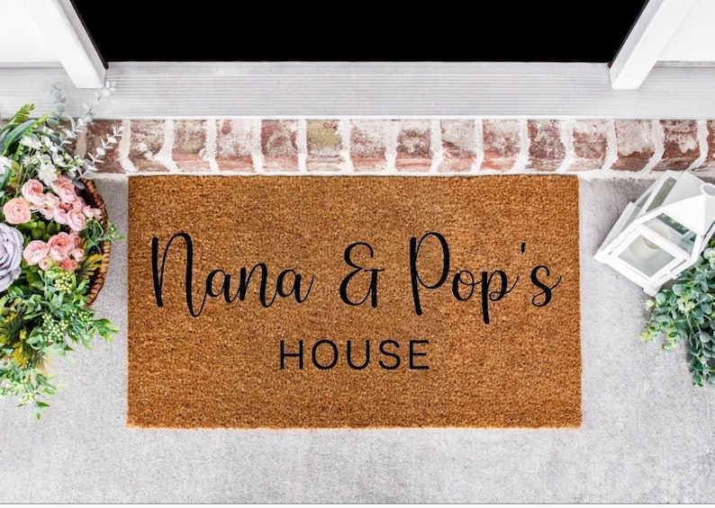 May include: A brown coir doormat with the text "Nana & Pop's House" in black cursive lettering.