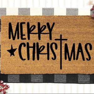 May include: A brown coir doormat with the text "Merry Christmas" in black lettering with a star and a cross.