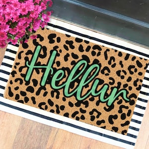 May include: A brown doormat with a leopard print design and the word "Hello" written in green cursive.