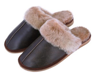 May include: A pair of dark brown leather slippers with a light brown fur trim. The slippers have a stitched seam down the center and a brown sole. The fur trim adds a touch of luxury and warmth to these cozy indoor shoes.