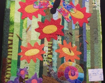 May include: A colourful quilt featuring a butterfly, flowers, and a snail. The quilt is made from a variety of fabrics and textures. It has been awarded a second-place ribbon at a quilt show.