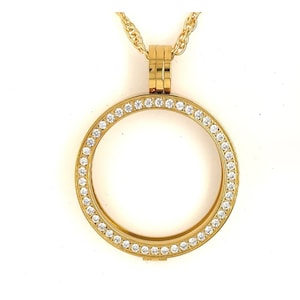 May include: A gold-tone pendant necklace with a round, clear crystal-encrusted bezel. The pendant is designed to hold a coin or other small object.