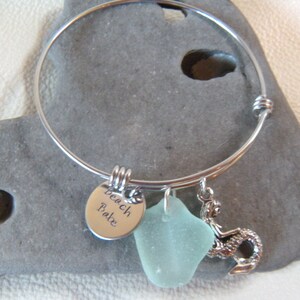 May include: A silver charm bracelet with a sea glass charm, a mermaid charm, and a charm that says "Beach Babe".